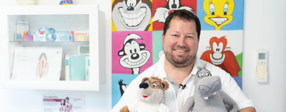 Dr. Gitt, lächelnd, mit Stofftieren für die kleinen Patienten im Arm.